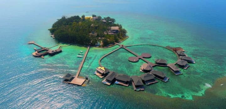 Pulau kecil dengan cottage terapung di atas laut toska